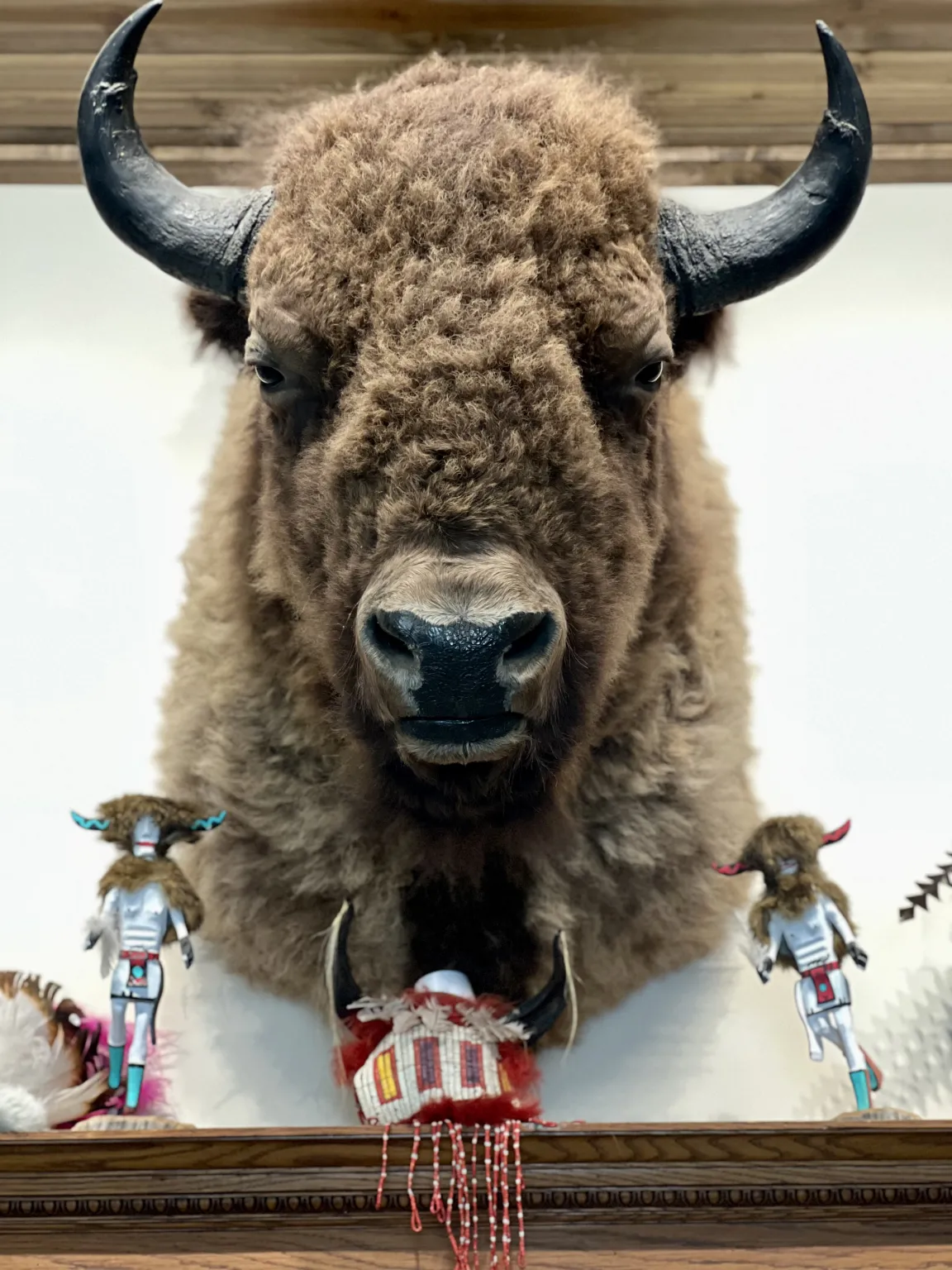 Bison head mount with decorative figures below.