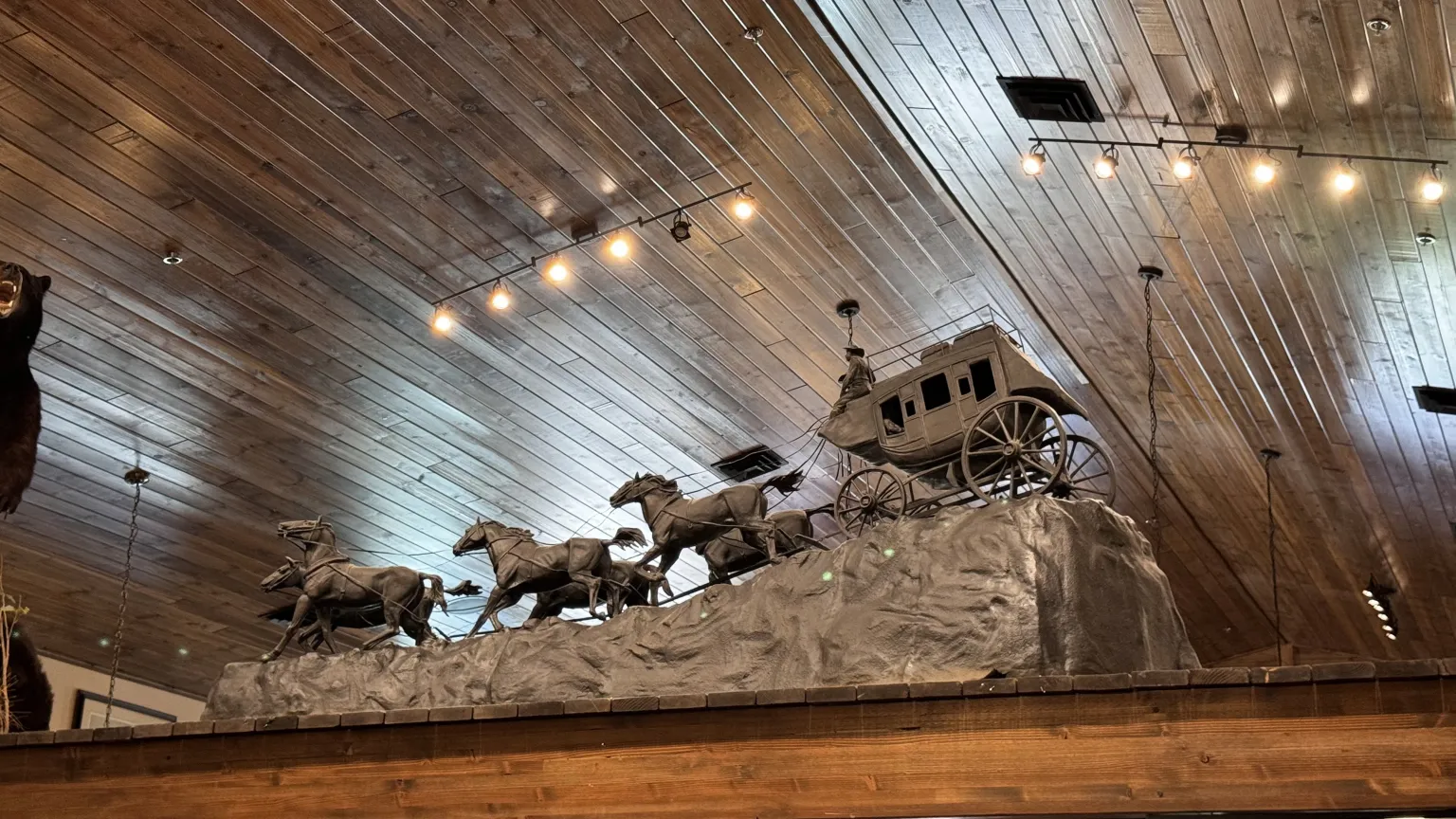 Stagecoach sculpture with horses on display.