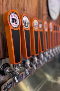 Orange beer taps lined up on wall.
