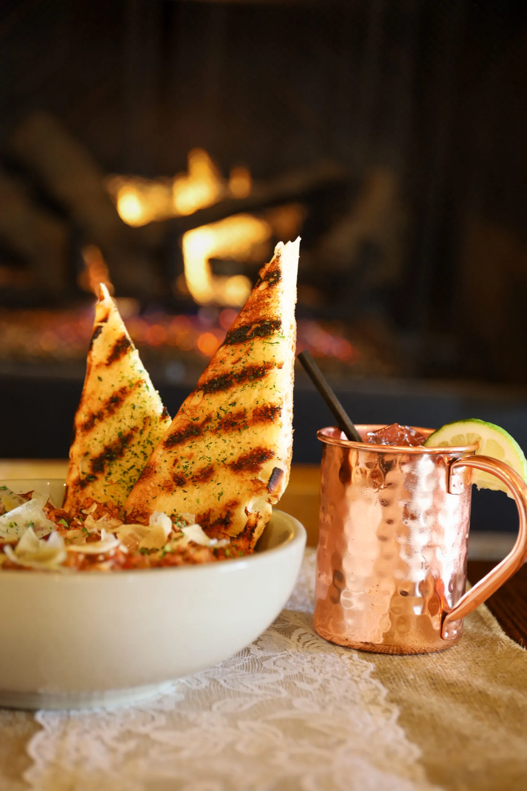 Grilled bread with drink by cozy fireplace.