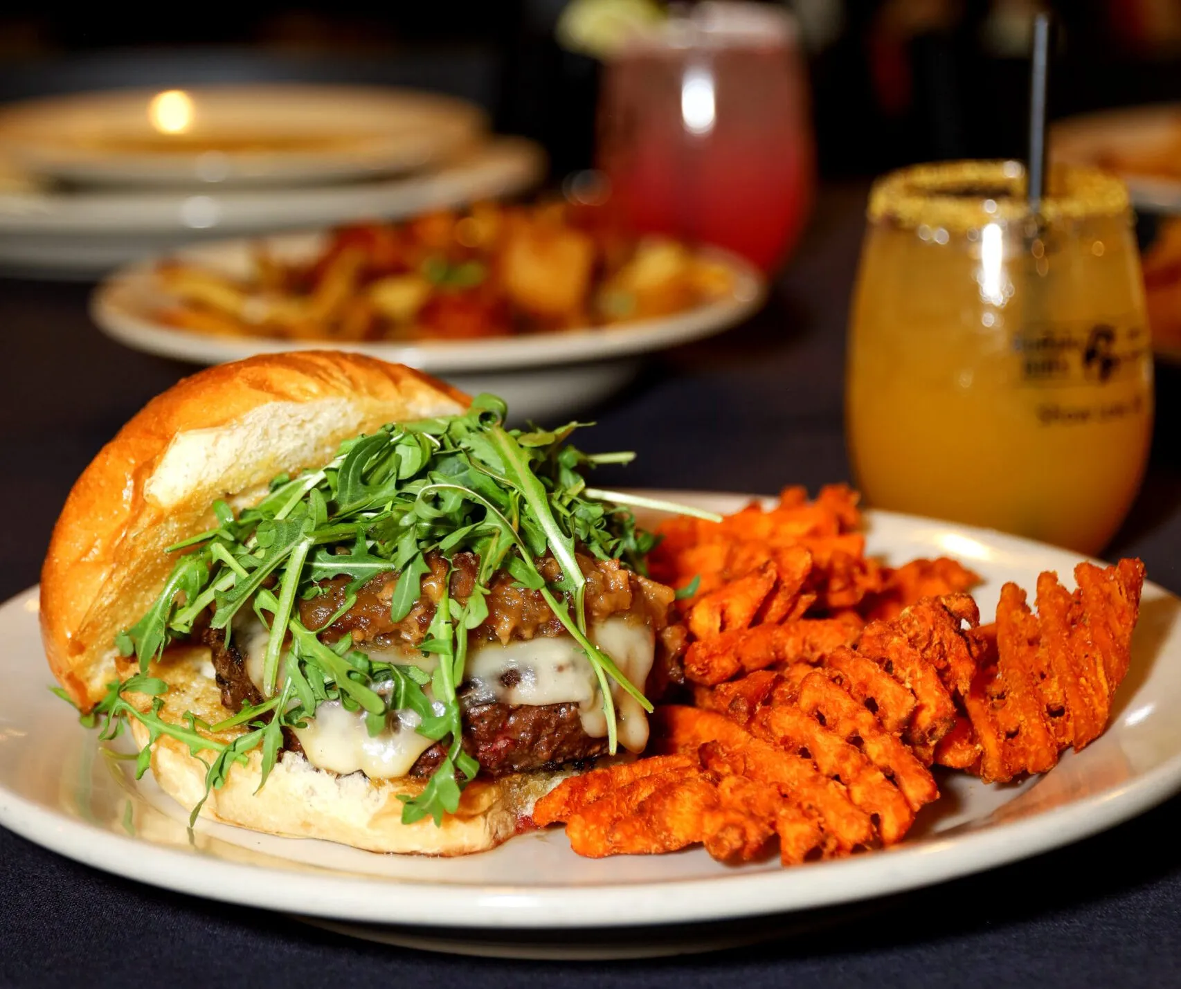 Burger with waffle fries and drinks.