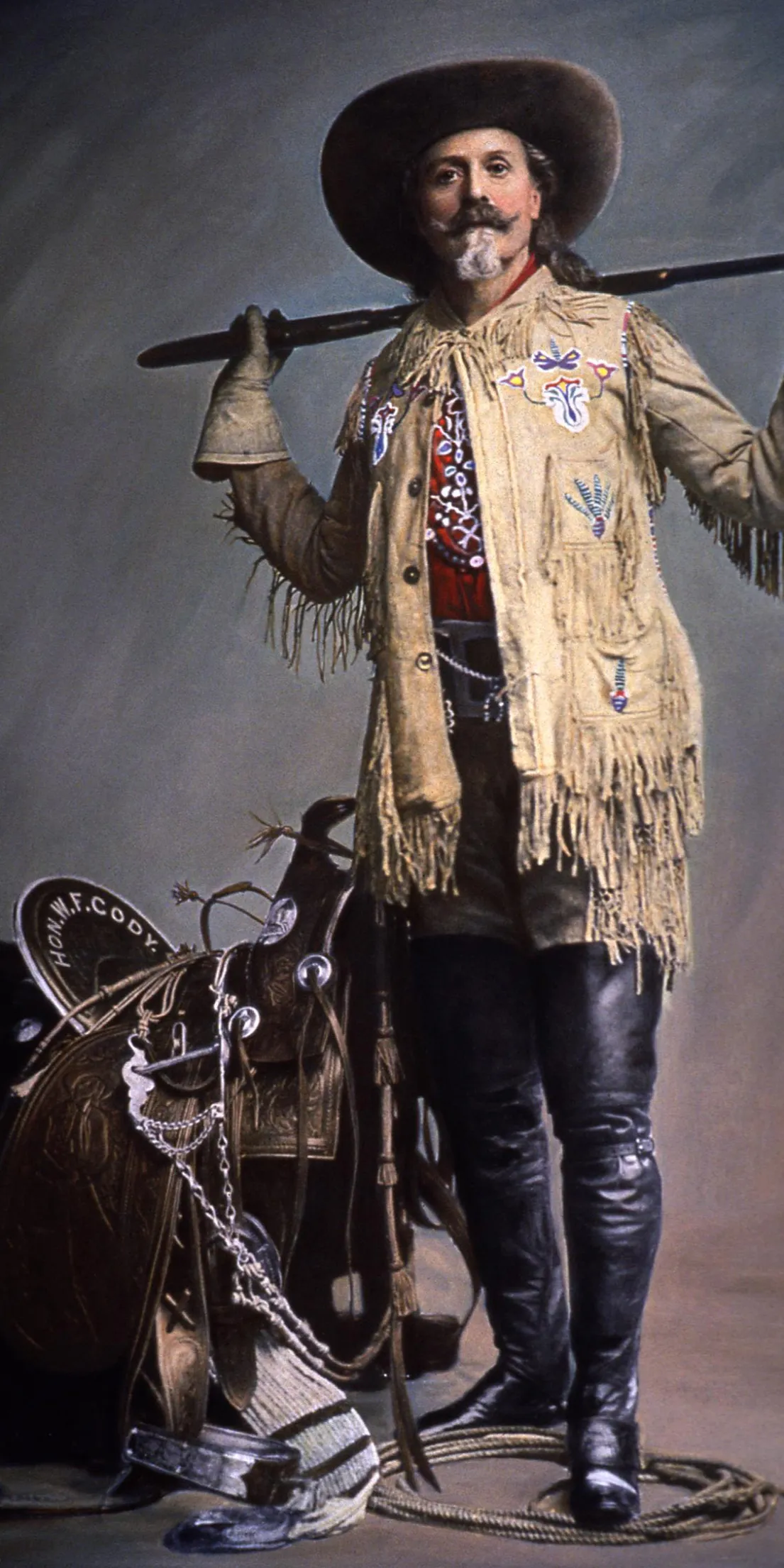 Man in cowboy attire with rifle.